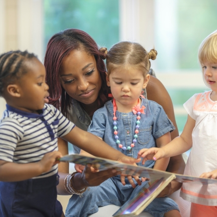 the teacher guides her curios students in reading a book