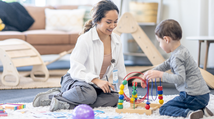 A woman occupational therapist carefully observing a child playing a toy