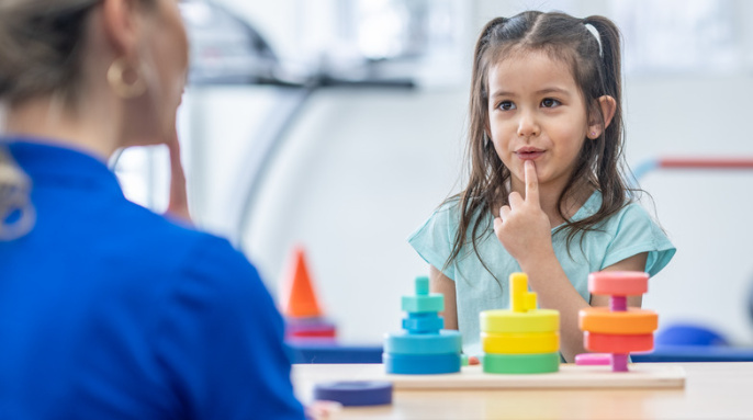 occupational therapist patiently supporting a child in an activity